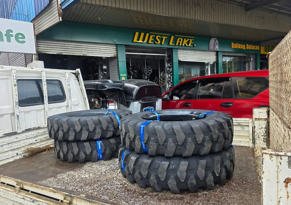 Heavy-equipment tires on a truck bed in front of the shop